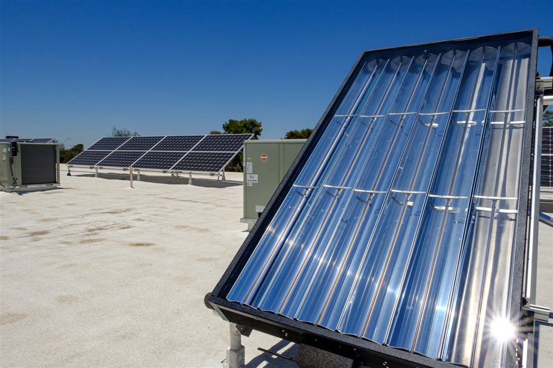 A solar coil collector installed on a commercial roof, rooftop units behind it
